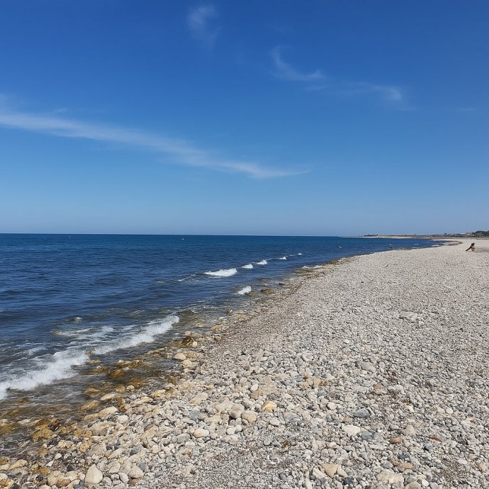 Spiaggia di ciottoli di Torre Quetta a Bari con mare calmo e cielo azzurro in estate.