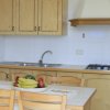 Cucina con mobili in legno chiaro, tavolo da pranzo e frutta fresca in esposizione.