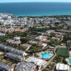 Veduta aerea di un villaggio turistico con piscina e campi sportivi vicino al mare.
