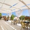 Terrazza coperta con sedie e tavolini vicino a fiori colorati.