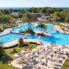 Ampia piscina con palme e ombrelloni, alberi sullo sfondo.
