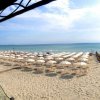 Spiaggia con file di ombrelloni bianchi e vista mare.