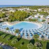 Grande piscina con ombrelloni e paesaggio verde.