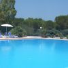 Ampia piscina all'aperto con lettini e ombrelloni, circondata da alberi.