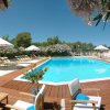 Piscina circondata da sedie a sdraio, ombrelloni bianchi e piante fiorite.