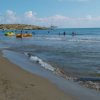 Spiaggia con persone in acqua e sulla sabbia.