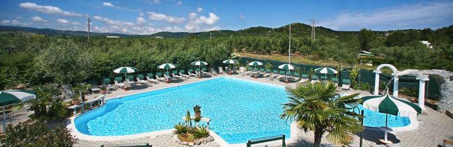 Una piscina all'aperto circondata da lettini e ombrelloni.