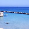 Piccola baia con mare turchese, barca e scogli.