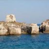 Un'antica torre diroccata su una scogliera circondata dal mare azzurro.