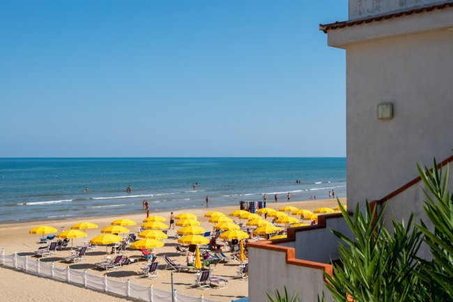 Spiaggia con ombrelloni gialli e mare calmo.