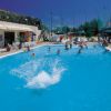 Piscina con persone che nuotano, ombrelloni verdi nelle vicinanze.