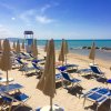 Ombrelloni chiusi su una spiaggia sabbiosa con mare turchese.