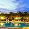 Piscina illuminata al tramonto con lettini e ombrelloni.