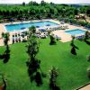 Due grandi piscine con lettini e ombrelloni su un prato verde.