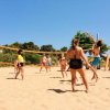 Gruppo gioca a pallavolo sulla sabbia.