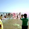 Persone sul bagnasciuga in festa con polveri colorate.