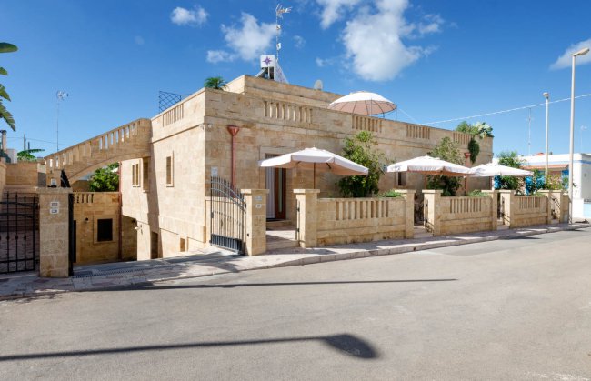Edificio in pietra con terrazza e ombrelloni.